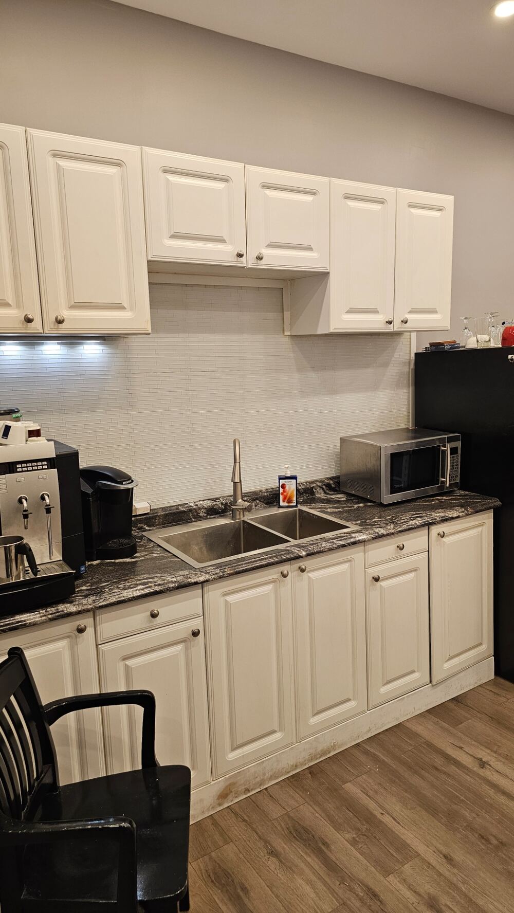Lower level kitchen with full-height white cabinetry, stone-look counters and double stainless steel sinks